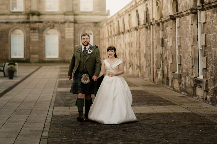 Bride and groom hold hands at The Venue, Eskmills